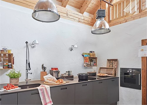 Highlight beim Umbau eines alten Bauernhofes ist der nach oben offene Kochbereich mit elektrisch zu öffnenden Velux Dachfenstern. Die hohe Decke besticht außerdem mit einer natürlichen Optik durch viel Holz. (Foto: Velux Deutschland GmbH)
