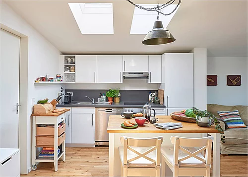 Herzstück dieser hellen Hamburger Dachgeschosswohnung ist der zentrale Wohn-Ess-Raum mit Loftcharakter. Die Velux Flachdach-Fenster über dem Küchenbereich sorgen für ein lichtdurchflutetes Ambiente. (Foto: Velux Deutschland GmbH)